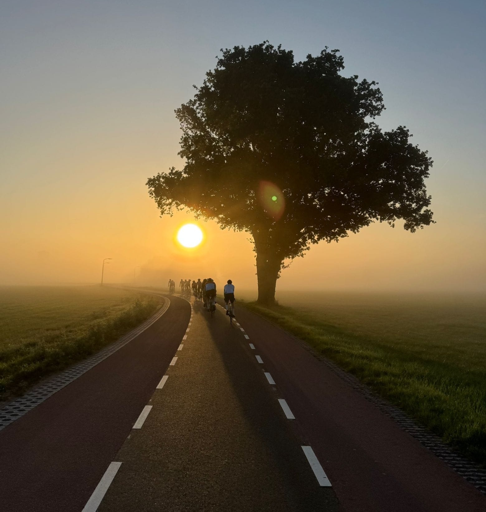 NoBreakfast fietsers bij zonsopgang op een Nederlandse polderwegweg
